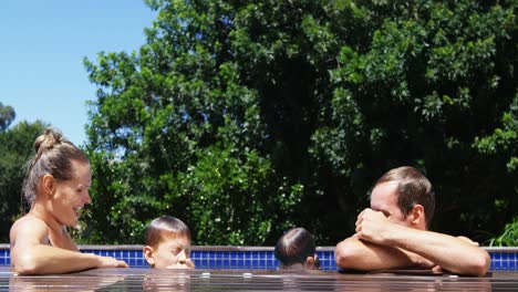 padres felices interactuando con los niños en la piscina