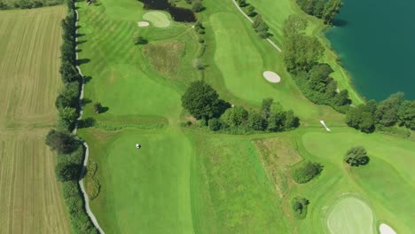 Cinematic-drone-footage:-A-captivating-top-down-view-of-an-Austrian-golf-resort-nestled-beside-the-emerald-waters-of-Mondsee-lake,-offering-serene-luxury