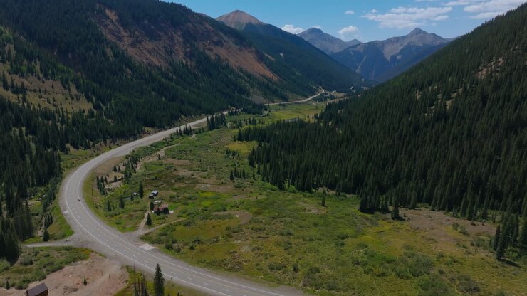 Curve iconiche dell'autostrada lungo una valle alpina aperta circondata dalle cime di San Juan, Million Dollar Highway, Colorado, USA.