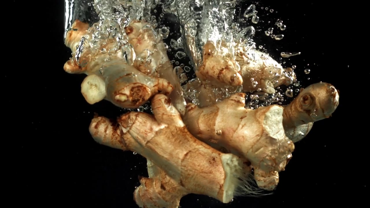 Fresh Ginger Roots Dropping into Water in Slow Motion