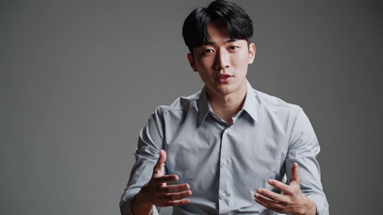 Mid-shot video of a man in a light shirt speaking against a neutral background