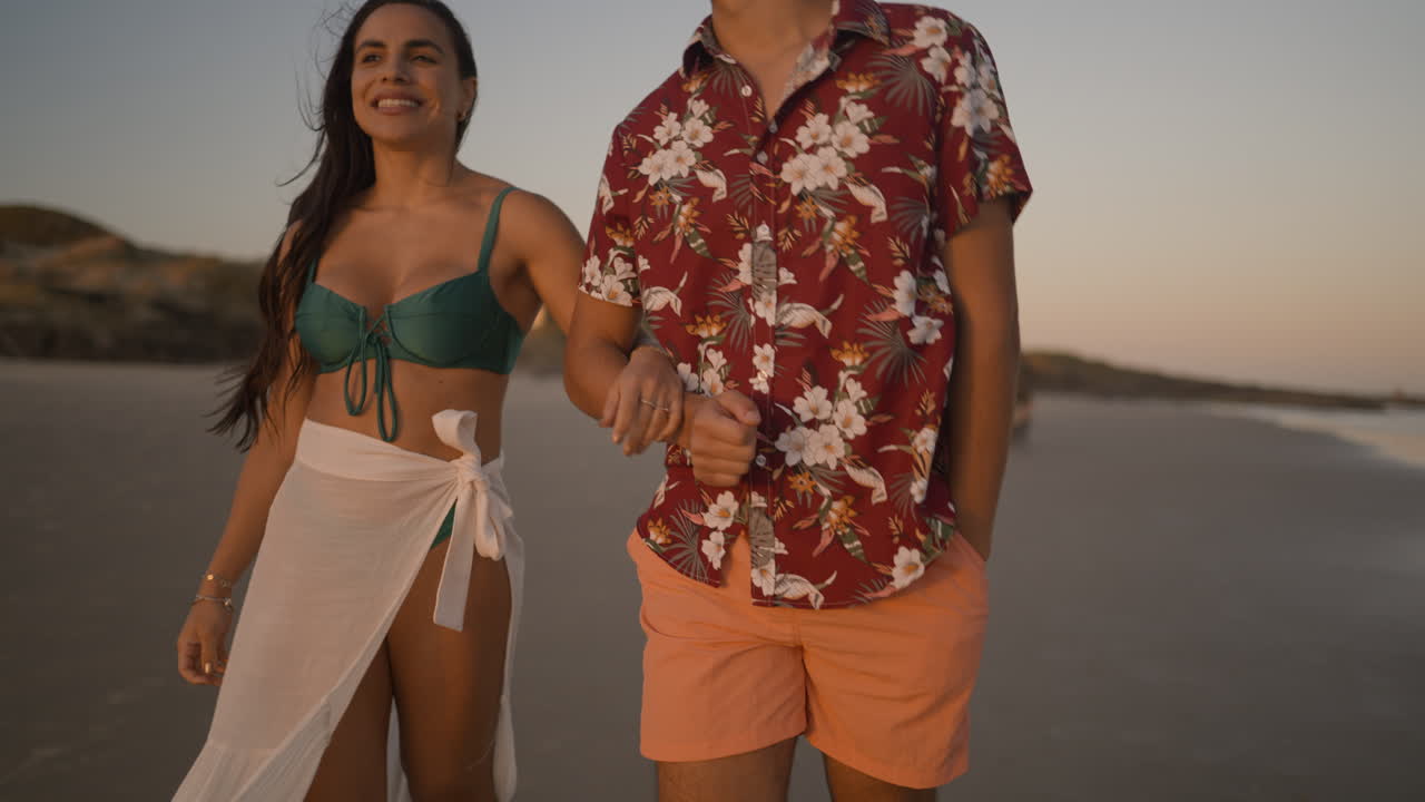 una pareja linda caminando por la playa.