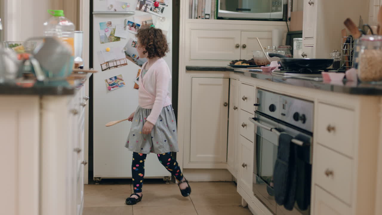 niña feliz bailando en la cocina divirtiéndose haciendo movimientos de baile divertidos disfrutando del fin de semana en casa