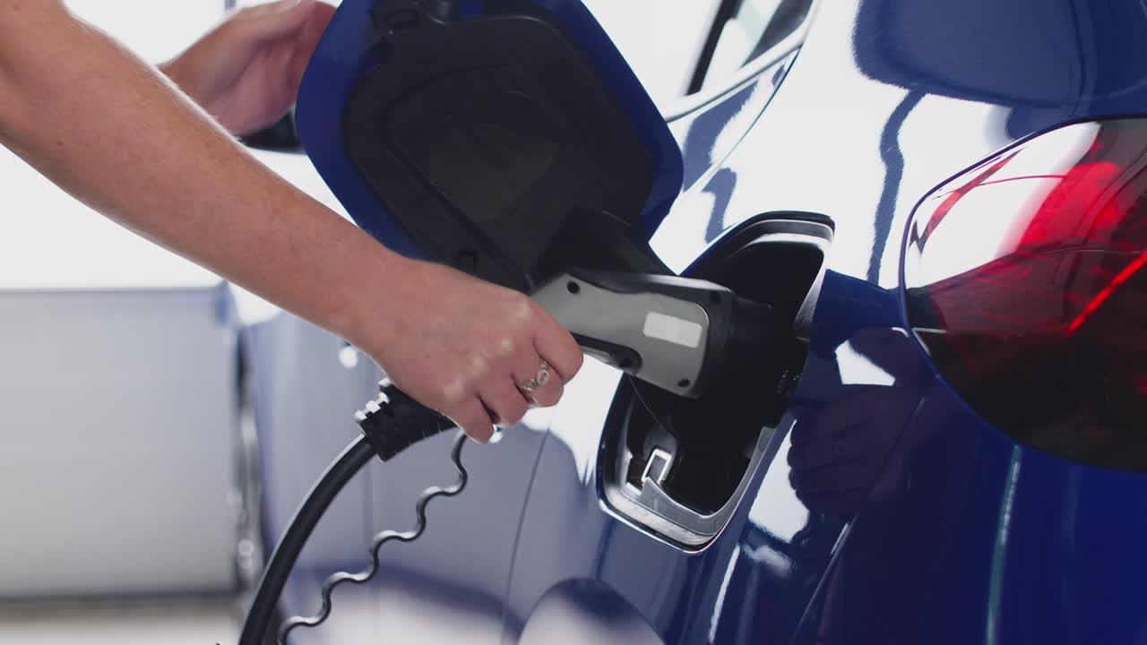 환경 친화적 인 제로 배출 전기 자동차에 충전 케이블을 연결하는 여성의 근접