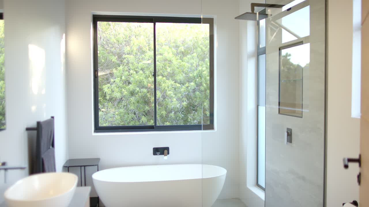 Modern bathroom with freestanding bathtub and large window overlooking greenery, copy space
