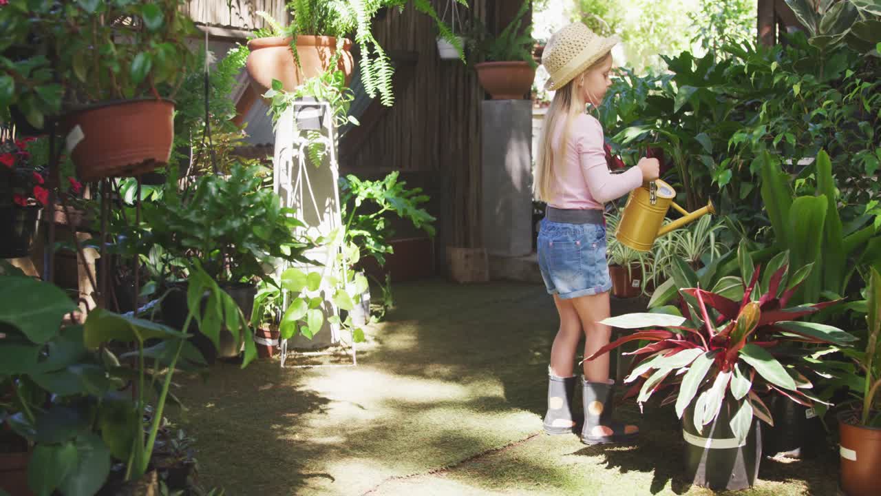 niña pequeña haciendo jardinería y regando una planta en un jardín botánico