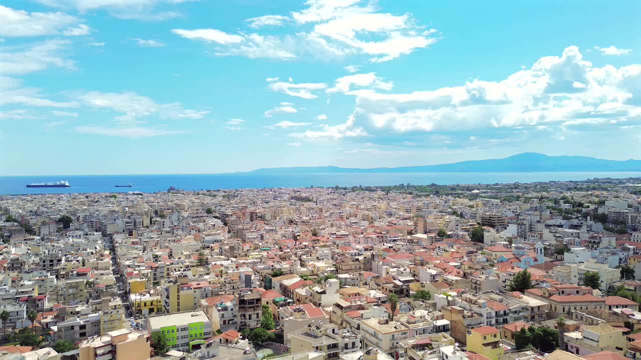 Aerial cityscape over Kalamata city, beautiful blue sky with white cloud formations , Messinian bay on the background, push in, raise up 4K footage
