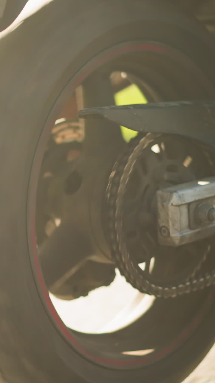 vista de las piernas de primer plano de dos mujeres montando una bicicleta eléctrica con una usando sandalias y la otra en zapatillas de deporte, las ruedas de la bicicleta están en movimiento, y la luz del sol se refleja en la hierba a lo largo de la carretera