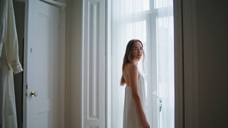 Tierna-Dama-Posando-En-El-Interior-De-La-Ventana.-Mujer-Mirando-Cámara-Relajándose-En-El-Dormitorio