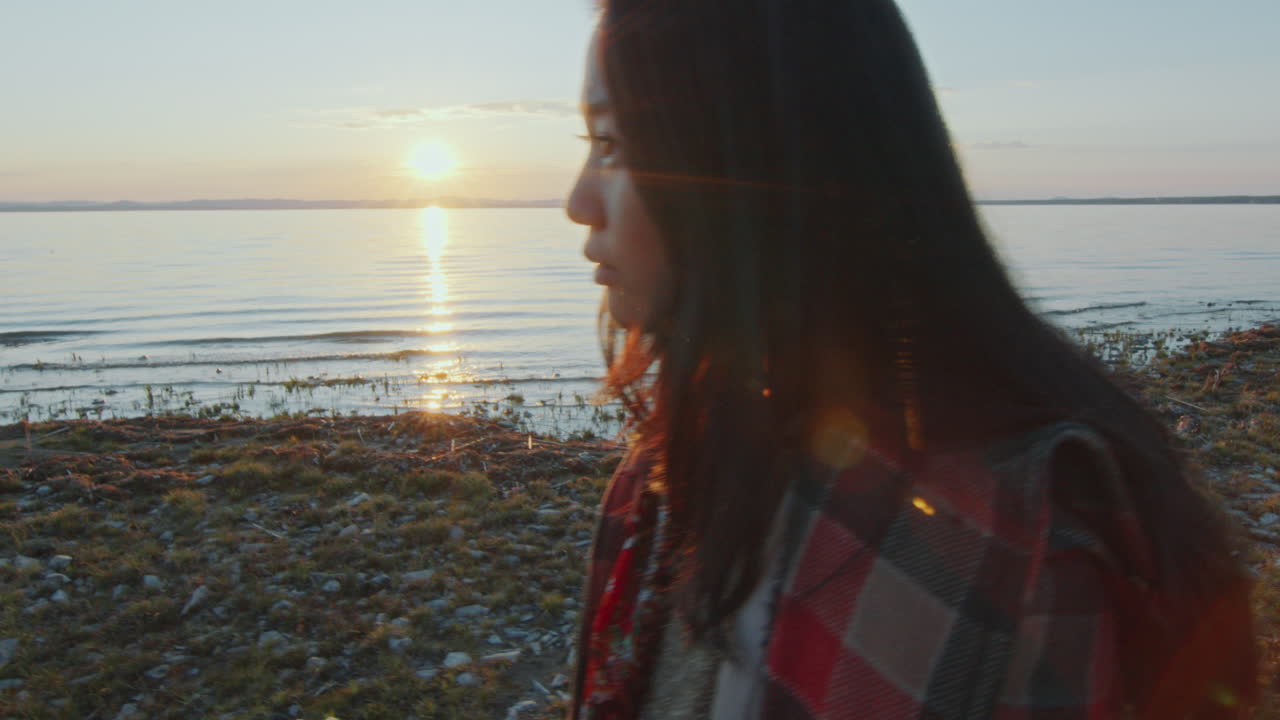 joven pensativa caminando a lo largo de la pacífica orilla del lago al atardecer