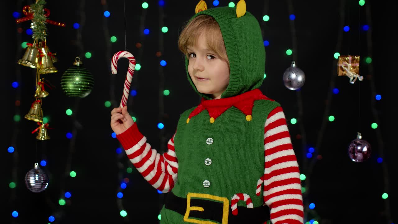Kid girl in Christmas elf Santa helper costume dancing, fooling around. New Year holiday celebration