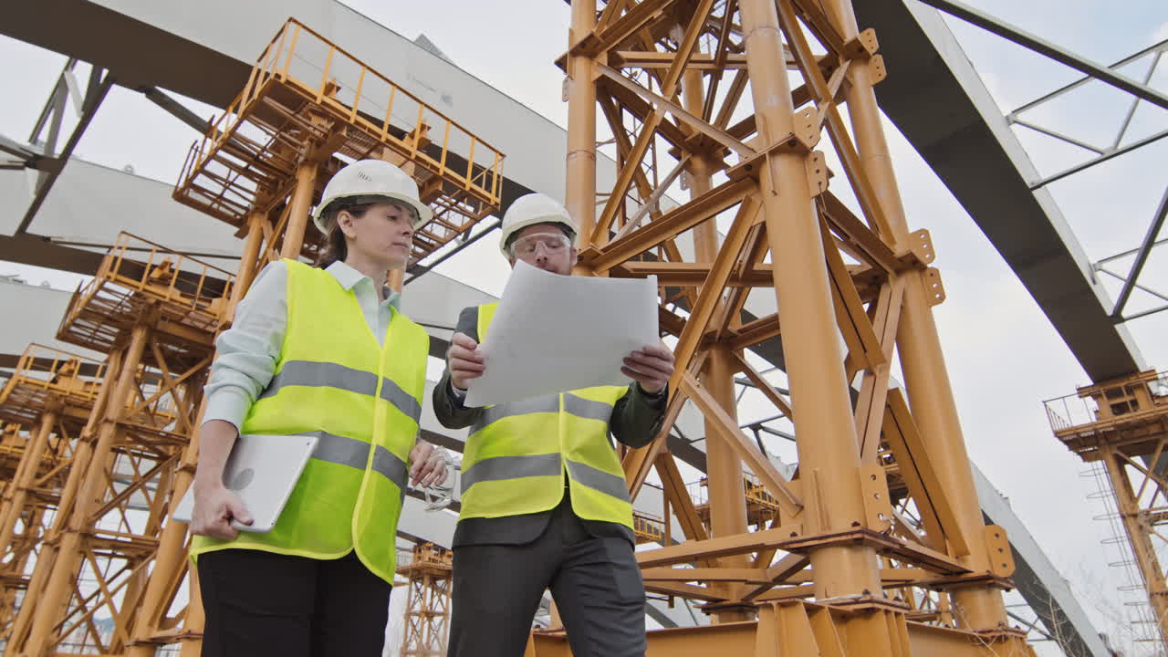 Female and Male Supervisors Inspecting Construction Site