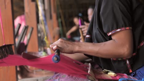 mulher levantando o liço estóico em um tear