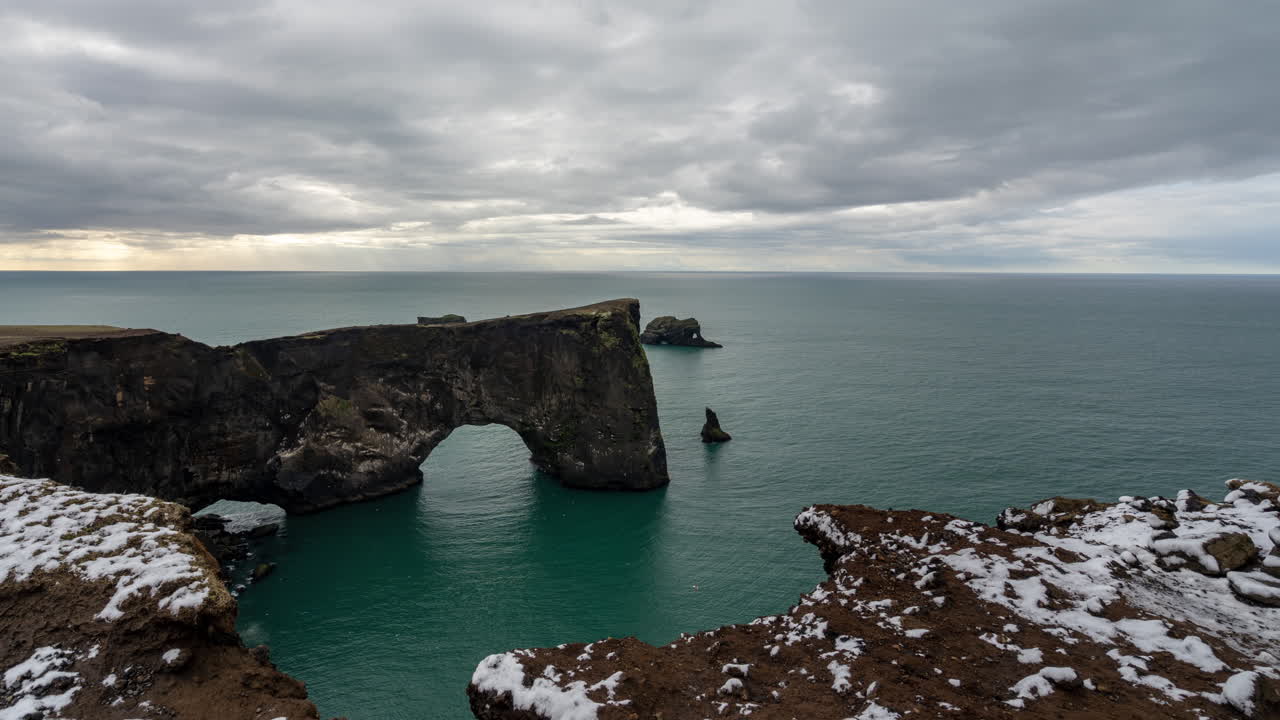 Dyrholaey Natural Arch, Iceland. Time Lapse of Cloudy Sky Above Landmark, Cliffs and Ocean Skyline