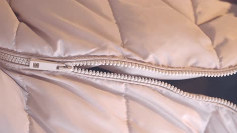 close-up of a zipper on a puffer jacket with a hand