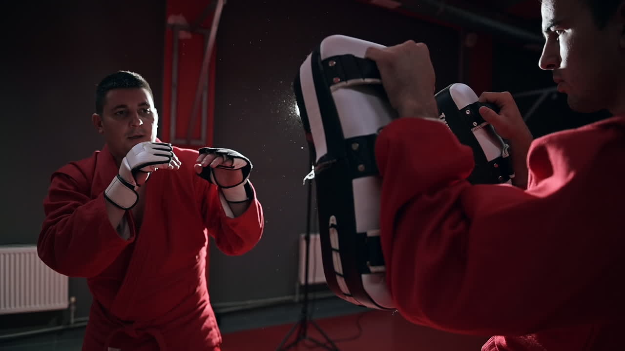 Taekwondo practitioner in a red kimono is training in a gym. Slow motion