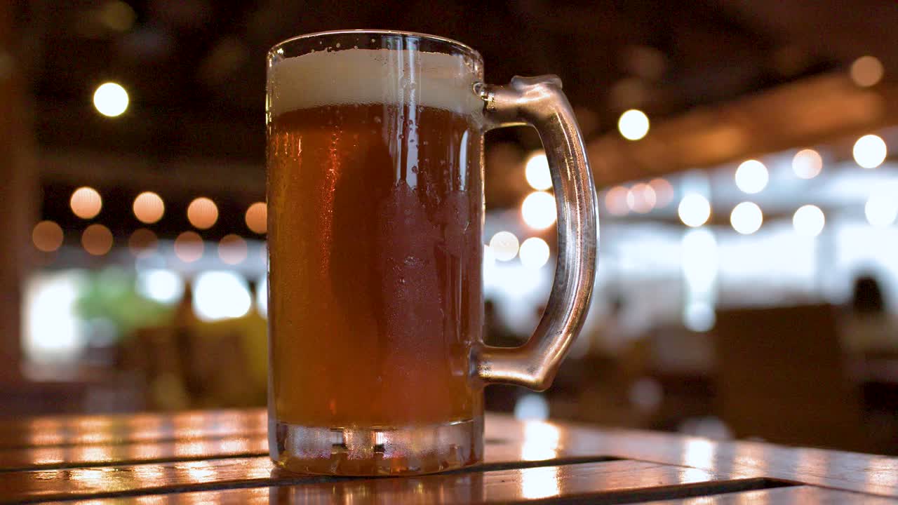 Primo piano di boccali di birra freddi con condensa su un tavolo in un bar poco illuminato