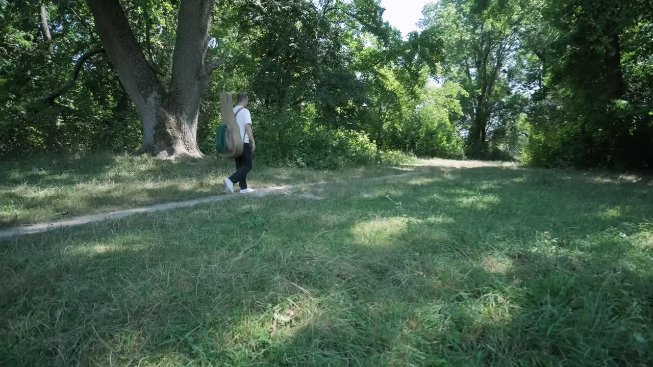 숲 근처의 거리에서 기타를 들고 는 젊은 남자