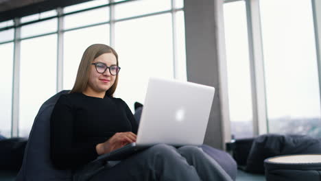 beautiful young woman in casual clothing using laptop and smiling while working indoors