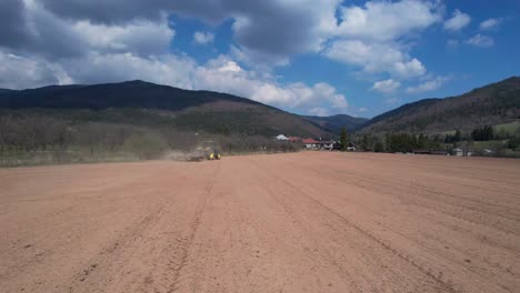 monoculture agriculture aerial drone shot of tractor pulling three heavy rollers