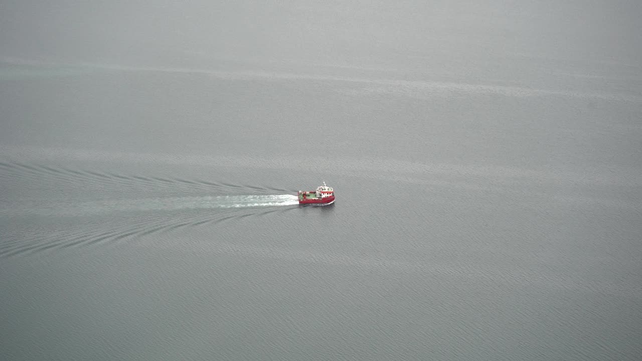 A small fishing boat moving in calm sea water in Iceland.