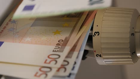 putting euros onto a radiator showing the high energy price concept. money