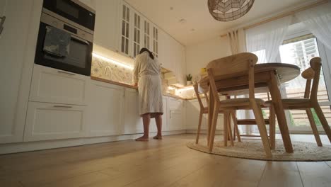 a pregnant woman enjoying her daily routine at home, relaxing in the living room and eating in the kitchen. the scene highlights comfort, maternity, and moments of self-care in a cozy setting