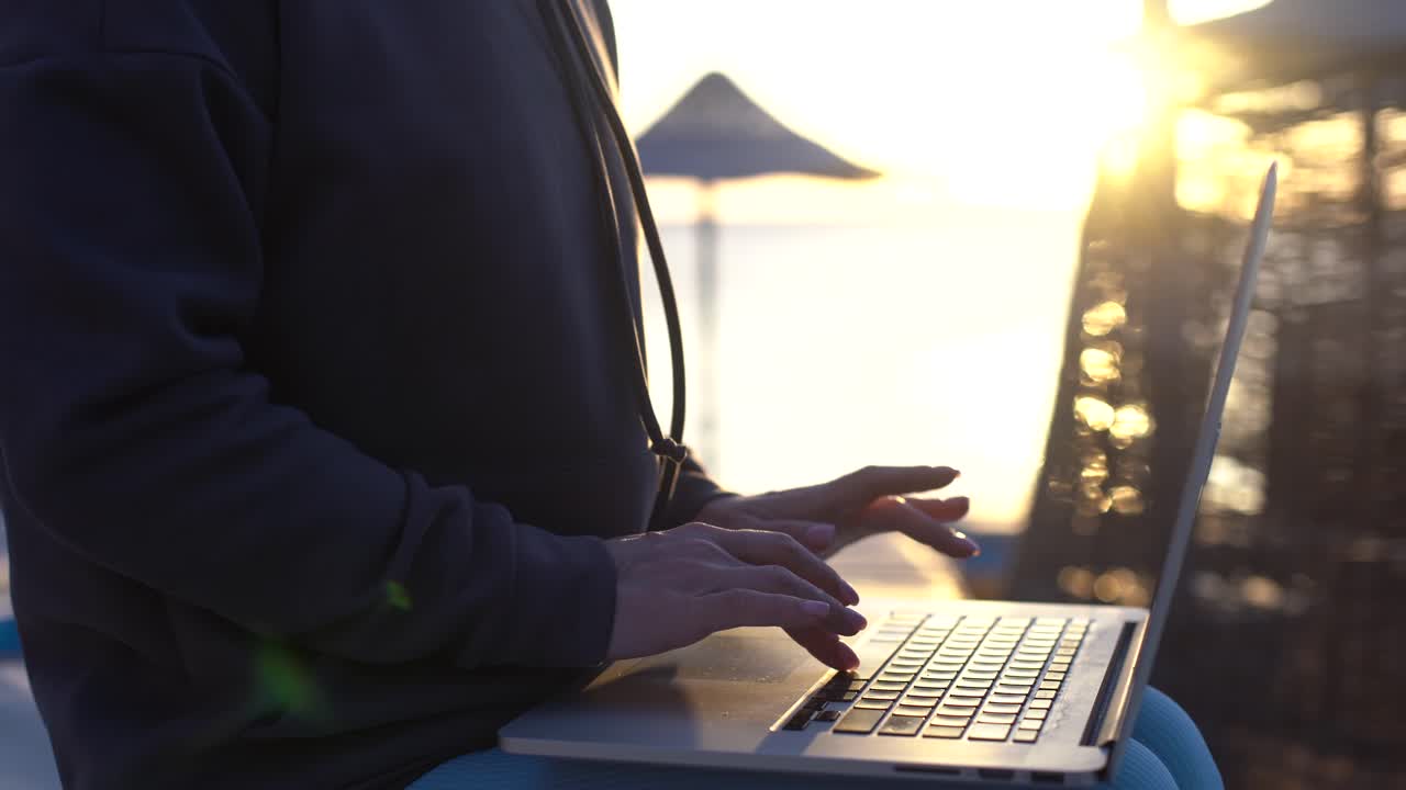 Young business woman using her laptop in cafe on sea background. Close up 4K