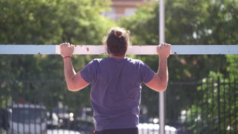 fit bearded man trains doing push ups on a soccer goal on a public park