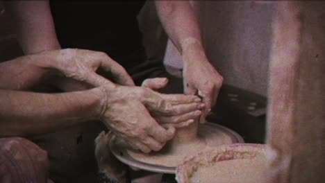 a potter teaches a woman to make clay dishes. a man takes a woman's hands. vintage effect.