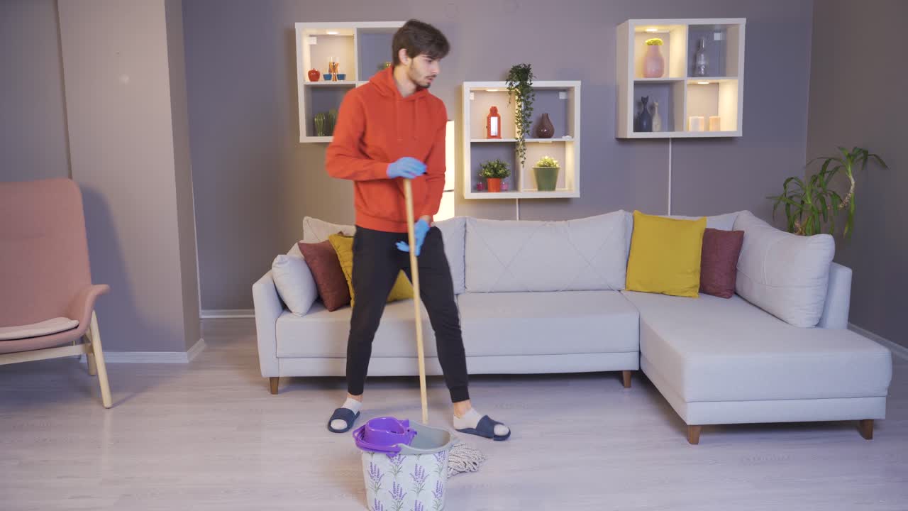 un joven limpiando la casa bailando, haciendo que su trabajo sea divertido.