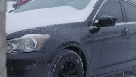 coche negro sentado en un camino de entrada durante una tormenta de invierno