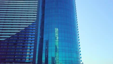 shot of reflections of sun, clouds and sky on glass windows of city skyscraper.