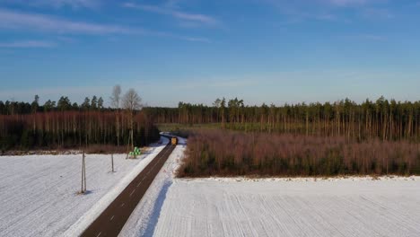 Log-truck-on-a-curvy-road-in-winter,-aerial-view