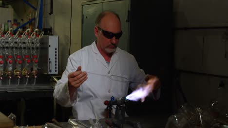 front view of mature caucasian male worker creating glass in glass factory 4k