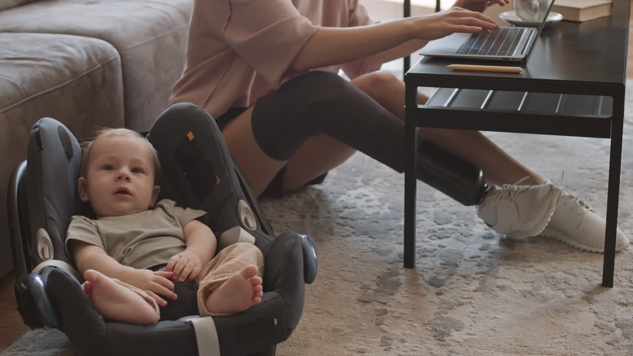 Toddler Lying in Baby Seat while Mother Working