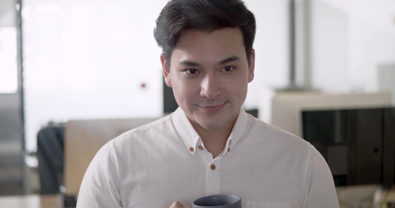 Un hombre se toma un momento para disfrutar de una pausa para el café en un entorno de oficina moderno, destacando el equilibrio entre vida laboral y personal y la relajación.