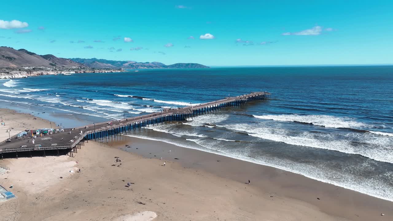 Vista aérea con dron del Muelle de Pismo Beach, hoteles en primera línea de playa con palmeras y la costa del Pacífico en un día despejado en Pismo Beach, California, EE. UU.