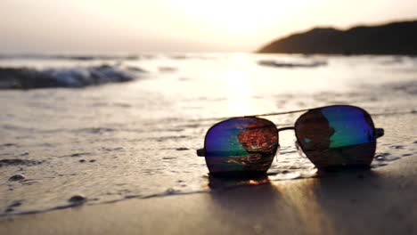 Olas-Del-Mar-Bañando-Gafas-De-Sol-Bajo-El-Sol-Soleado