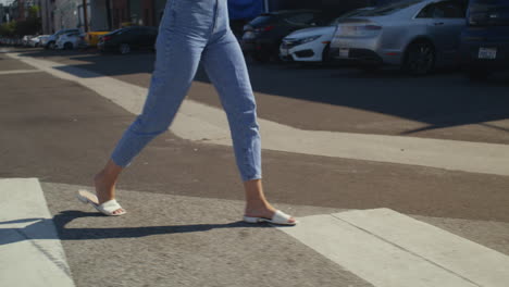 las piernas de una mujer desconocida caminando por el cruce de peatones. una chica irreconocible cruzando la carretera.