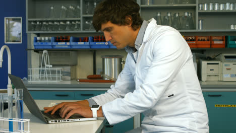 scientist using laptop while writing on paper