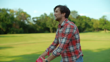 man holding ball in hands outside. smiling guy talking with somebody in park