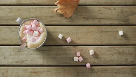 video of cup with coffee and marshmallows on wooden surface