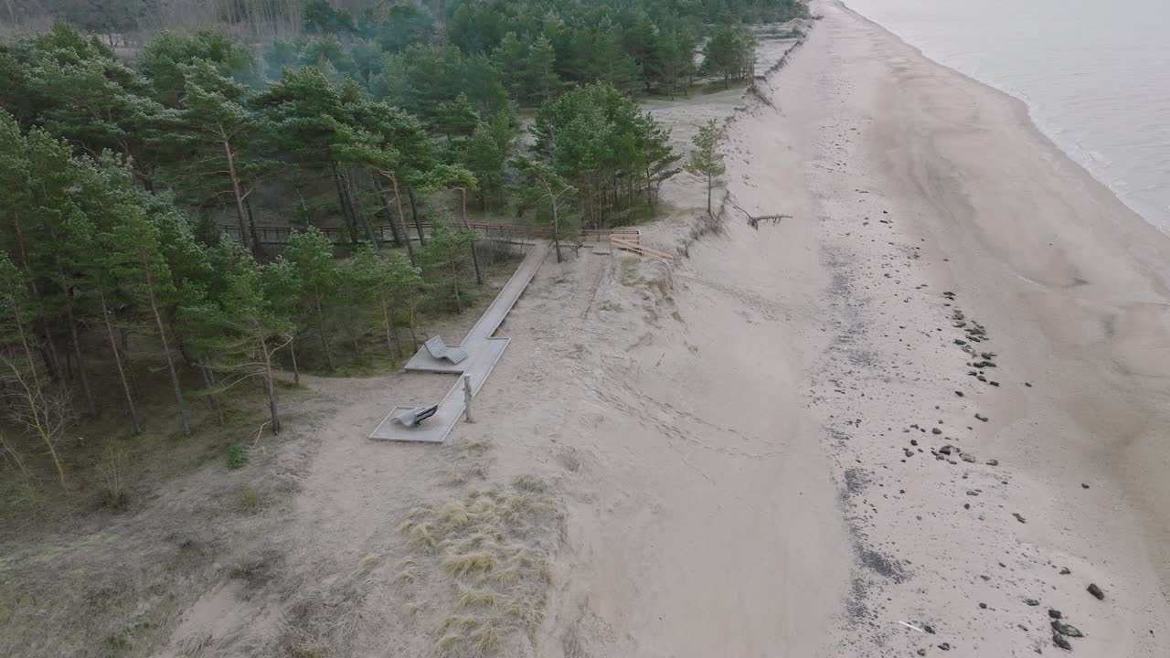 красивый вид с воздуха на побережье балтийского моря, пасмурный зимний день, спокойный пляж с белым песком, сосновый лес, эрозия берегов, изменения климата, широкий снимок с беспилотника, движущийся вперед, наклон вниз
