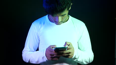 joven usando un teléfono inteligente en la iluminación del estudio