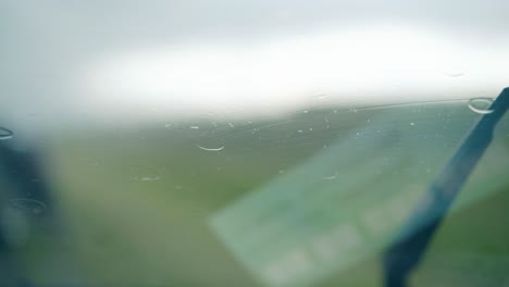 close view black metal wiper cleans raindrops from windshield