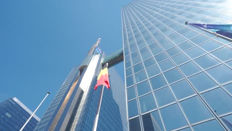 belgian flag waving slightly in front of glass business building facade in brussels, belgium