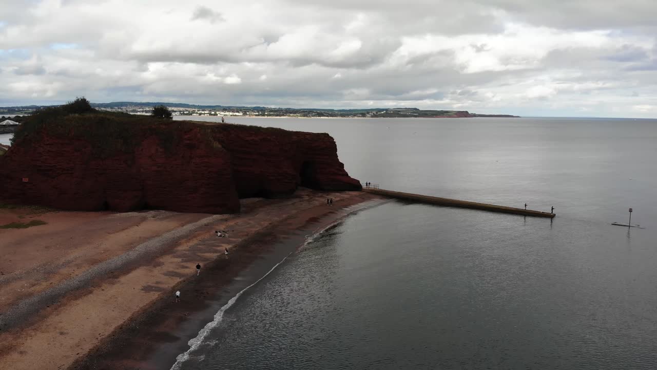 Aerial perspective of Dawlish's coastline featuring prominent red sandstone formations. push forward shot