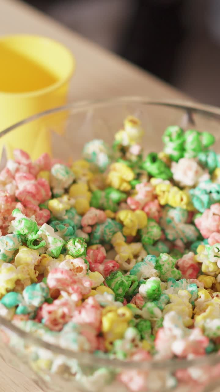 Hands mixing colorful popcorn in a bowl
