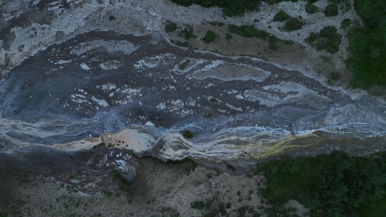 아이슬란드의 게이시르 근처의 활기찬 지열 유출 패턴의 드론 뷰, 독특한 텍스처와 광물이 풍부한 지형을 보여줍니다.